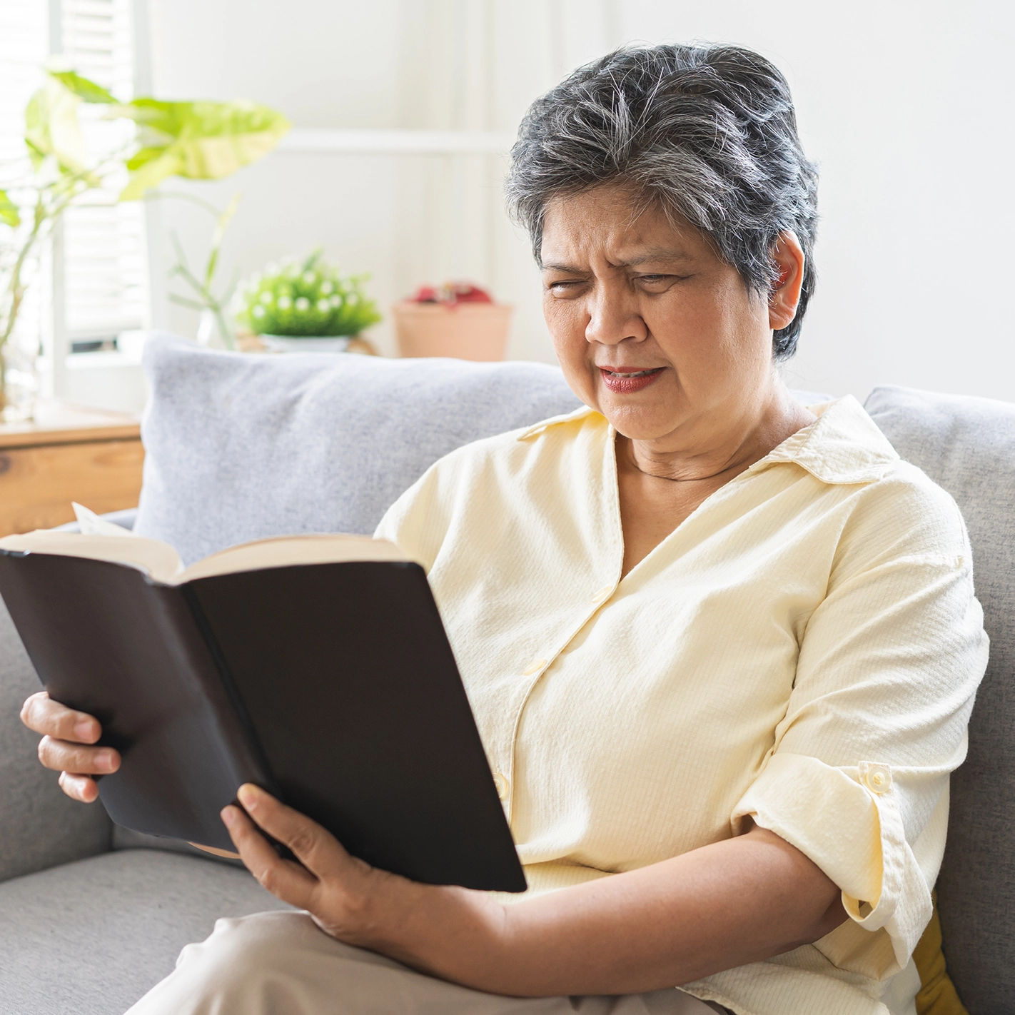 Senior woman struggling to read due to blurry vision after cataract surgery